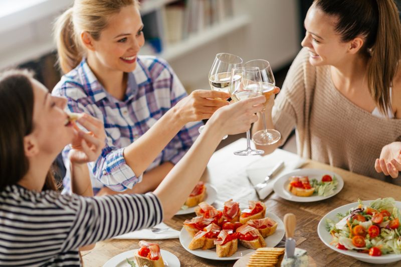 Freunde stossen beim Essen mit Wein an.
