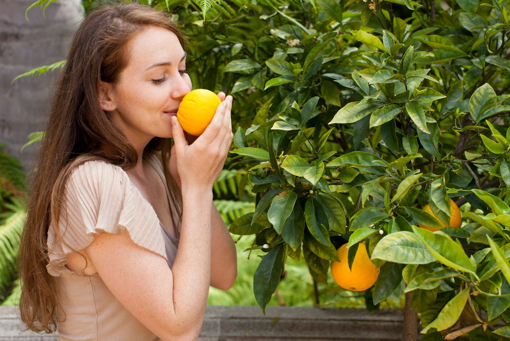 Eine Frau riecht an einer Orange.