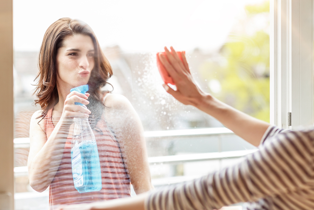 Frau putzt Fensterscheibe