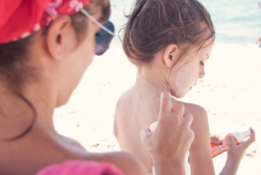 une mère met de la crème solaire