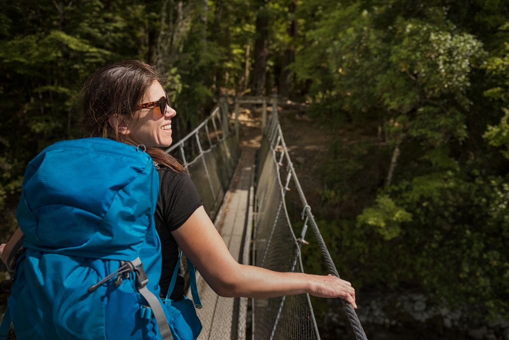 Frau auf Hängebrücke mit Rucksack