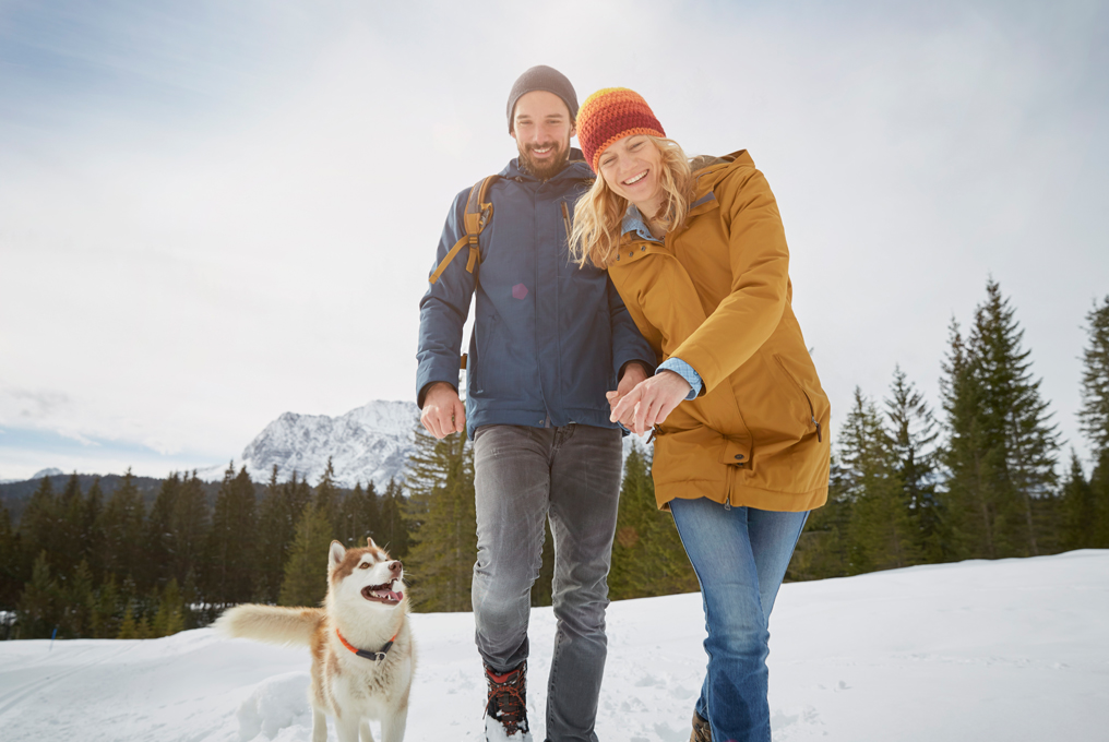 Una coppia innamorata che cammina nella neve con un cane