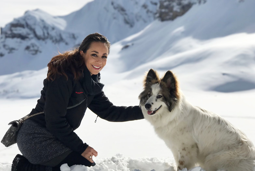 Eine hübsche junge Frau mit einem Hund im Schnee