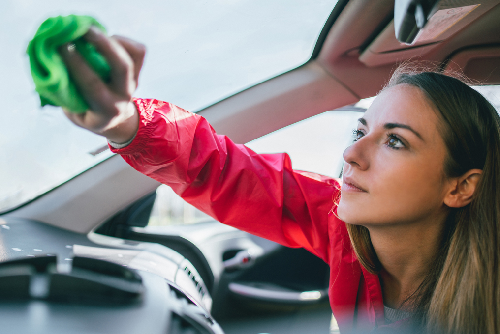 Una giovane donna sta pulendo il finestrino della macchina.