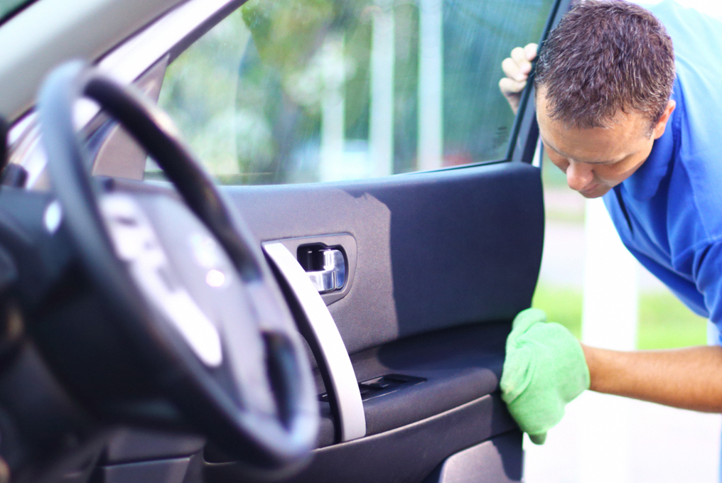 Ein Mann putzt sein Auto von innen.