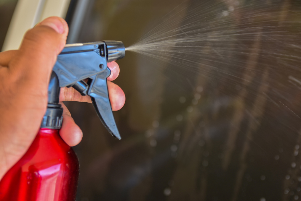 Man putzt die Fenster vom auto mit Fensterreiniger.