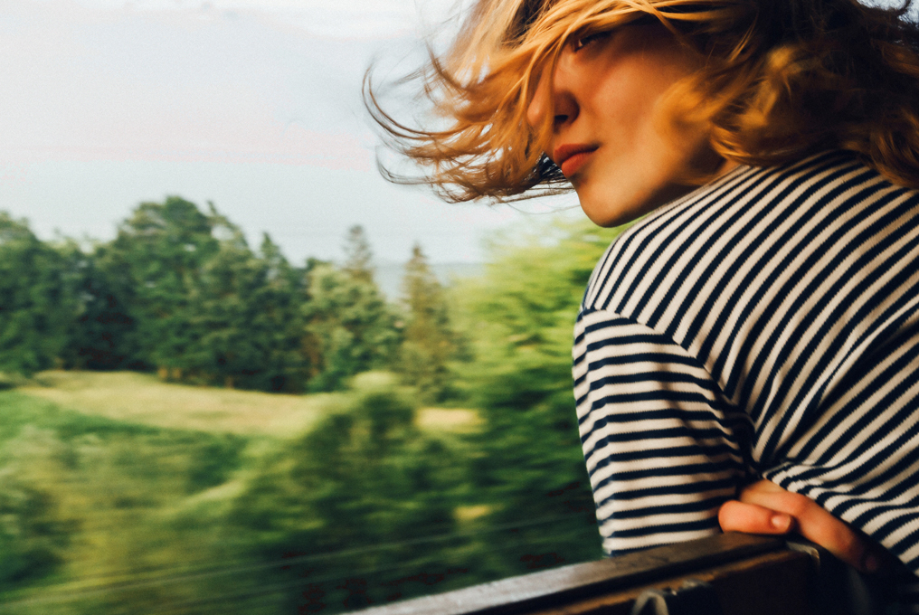 Un bambino guarda fuori dal finestrino mentre guida. Capelli che volano sul viso