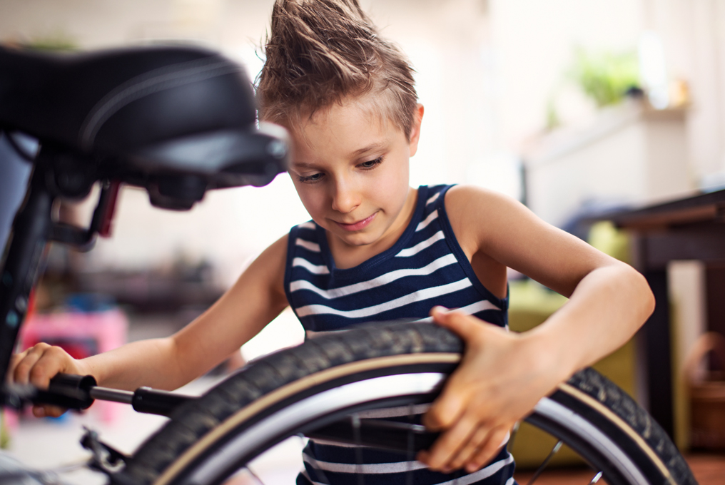 Ein kleiner Junge pumpt sein Velo auf.