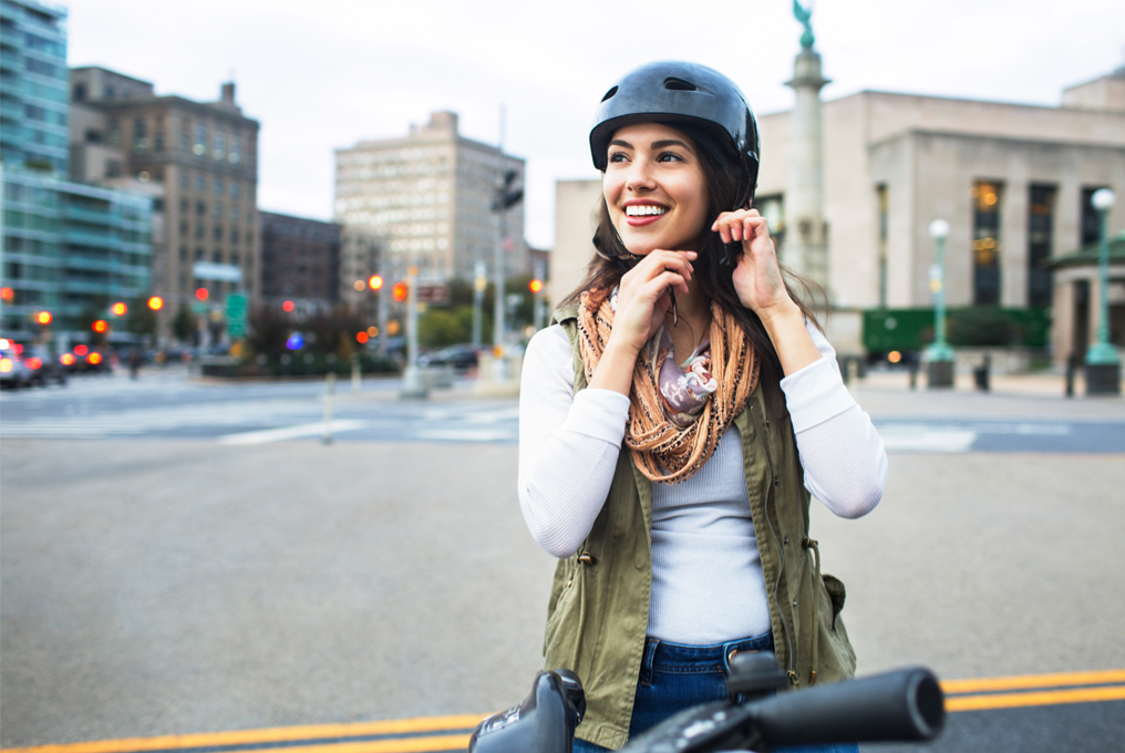 Eine hübsche junge Frau zieht sich einen schicken Helm an.