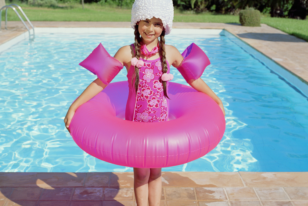Bambina con la gomma rosa e le ali di nuoto.
