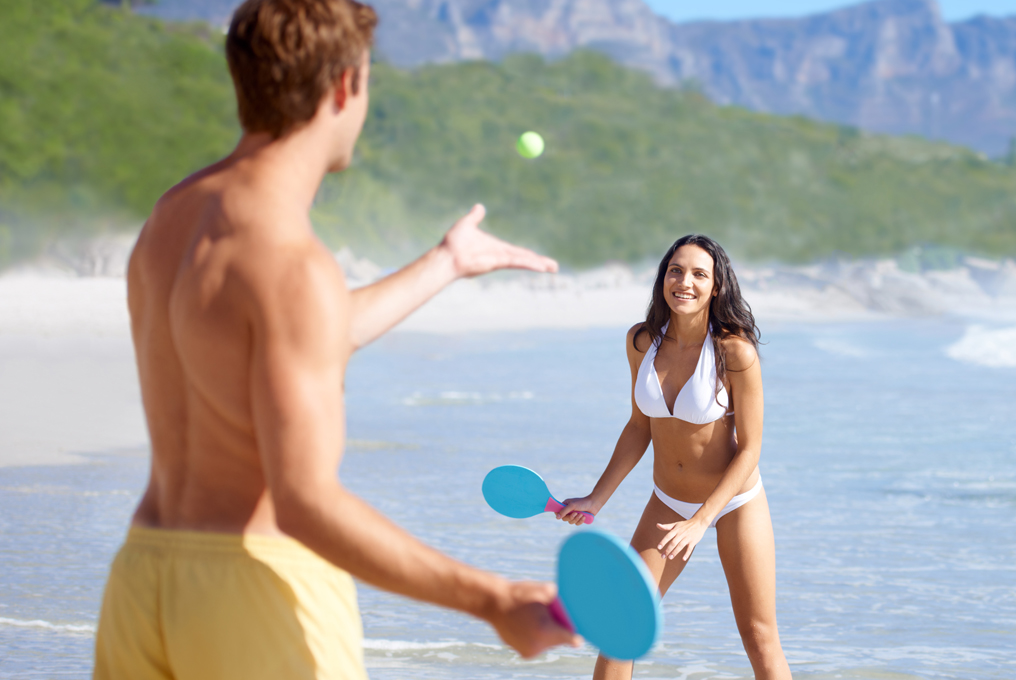 Donna e uomo che giocano sulla spiaggia.