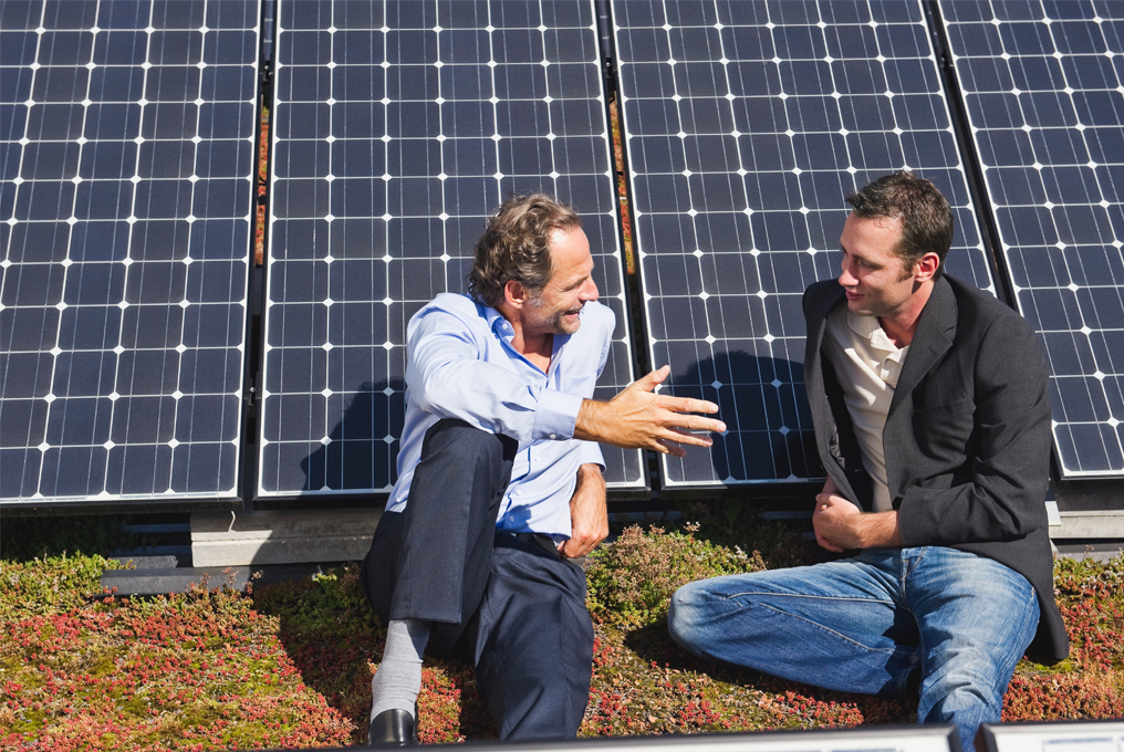 Zwei Herren lehnen sich gemütlich an die Solaranlage während sie sich unterhalten.