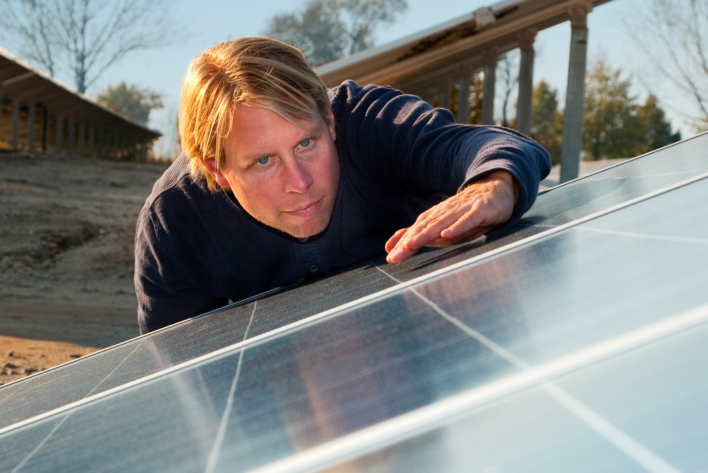 Ein Mann lehnt sich über das Solardach wegen einer Kontrolle.