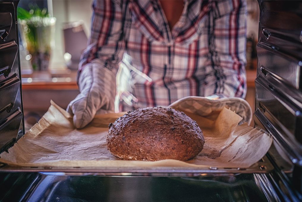 Eien Frau holt Frisch gebackenes Brot aus dem Offen