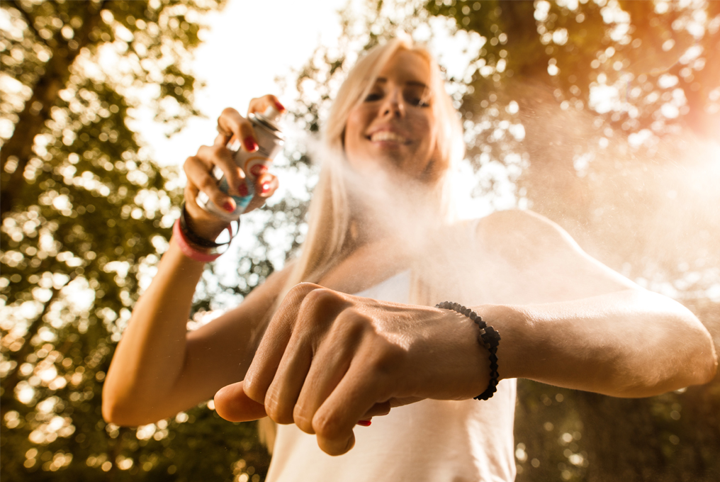 Eine Frau sprüht Insektenschutzmittel auf ihren Arm