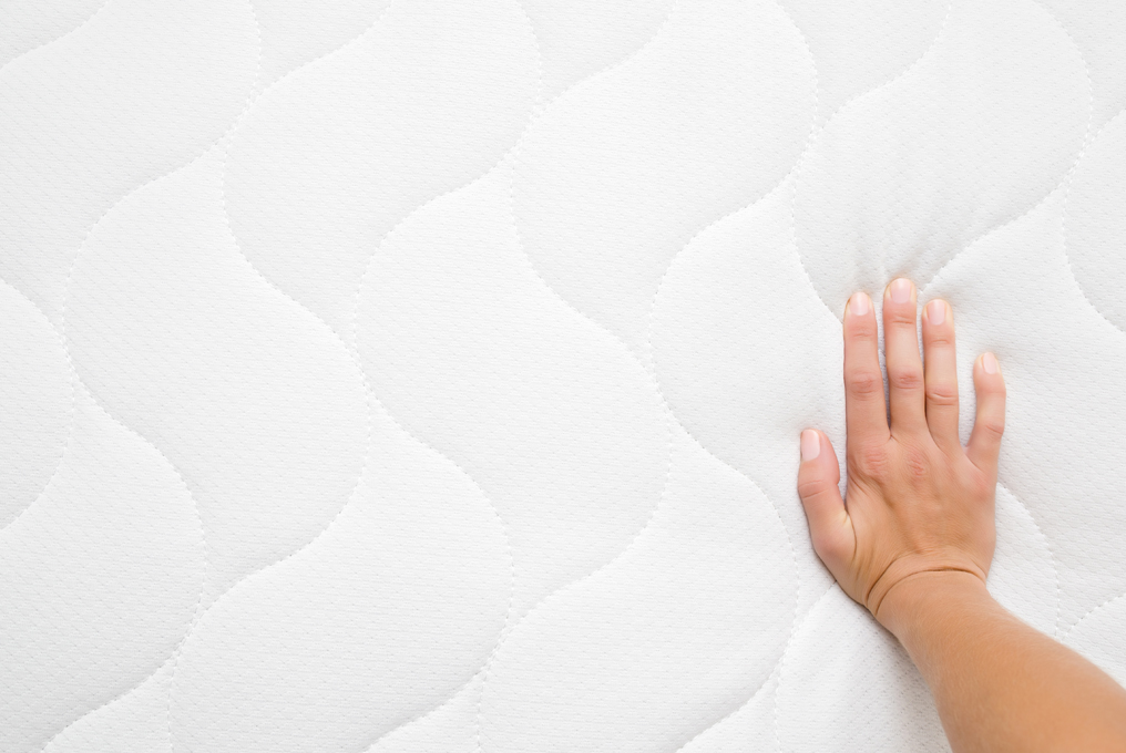 Eine Hand auf einer Matratze