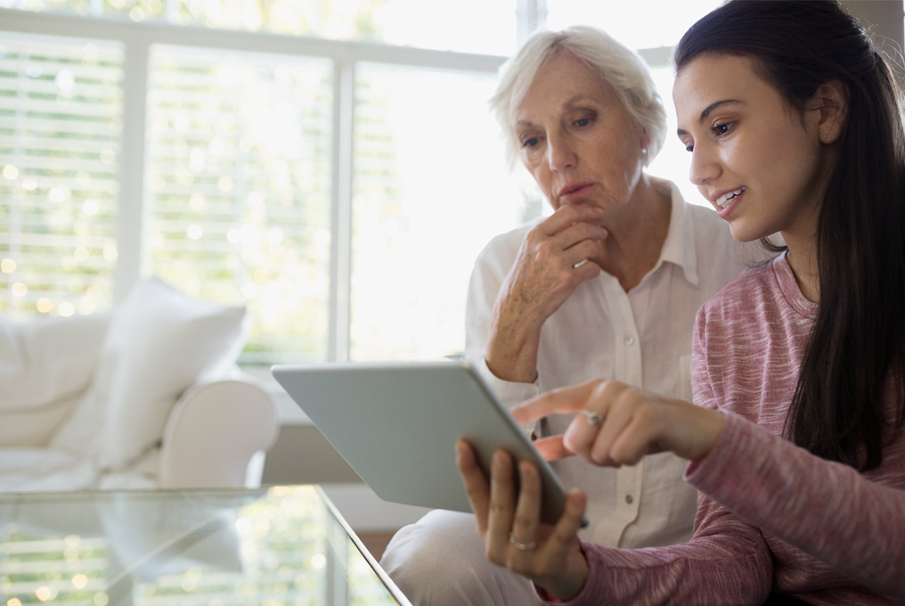 Una giovane donna mostra a una donna anziana come funziona un iPad