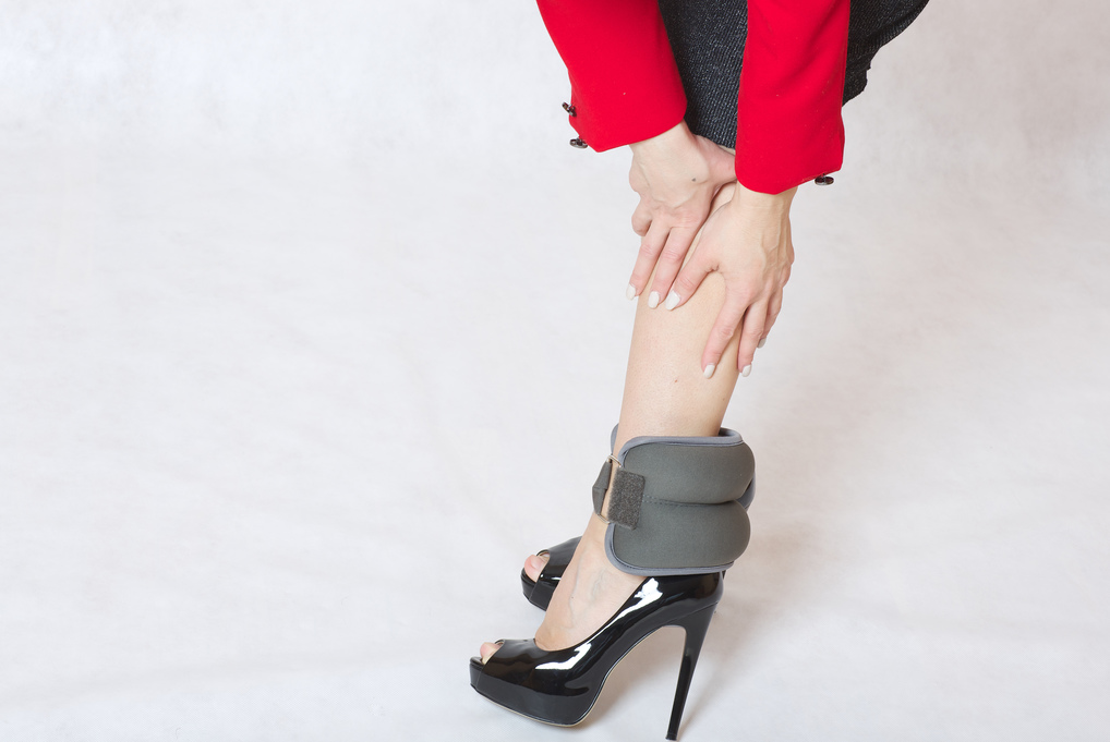 Frau in Highheels mit Gewichten an Fessel