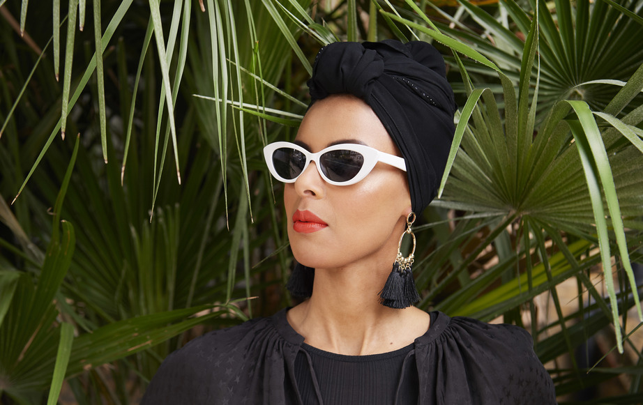 Frau mit Kopftiuch und Sonnenbrille vor Palme