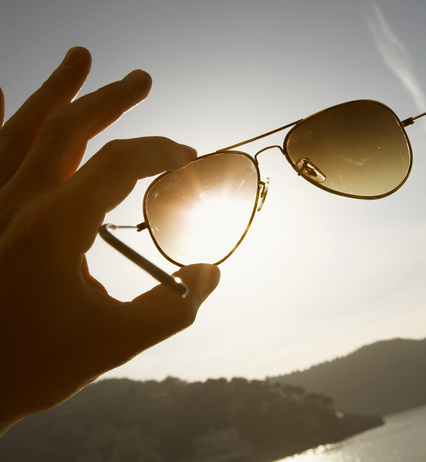 Hand hält Sonnenbrille in die Sonne