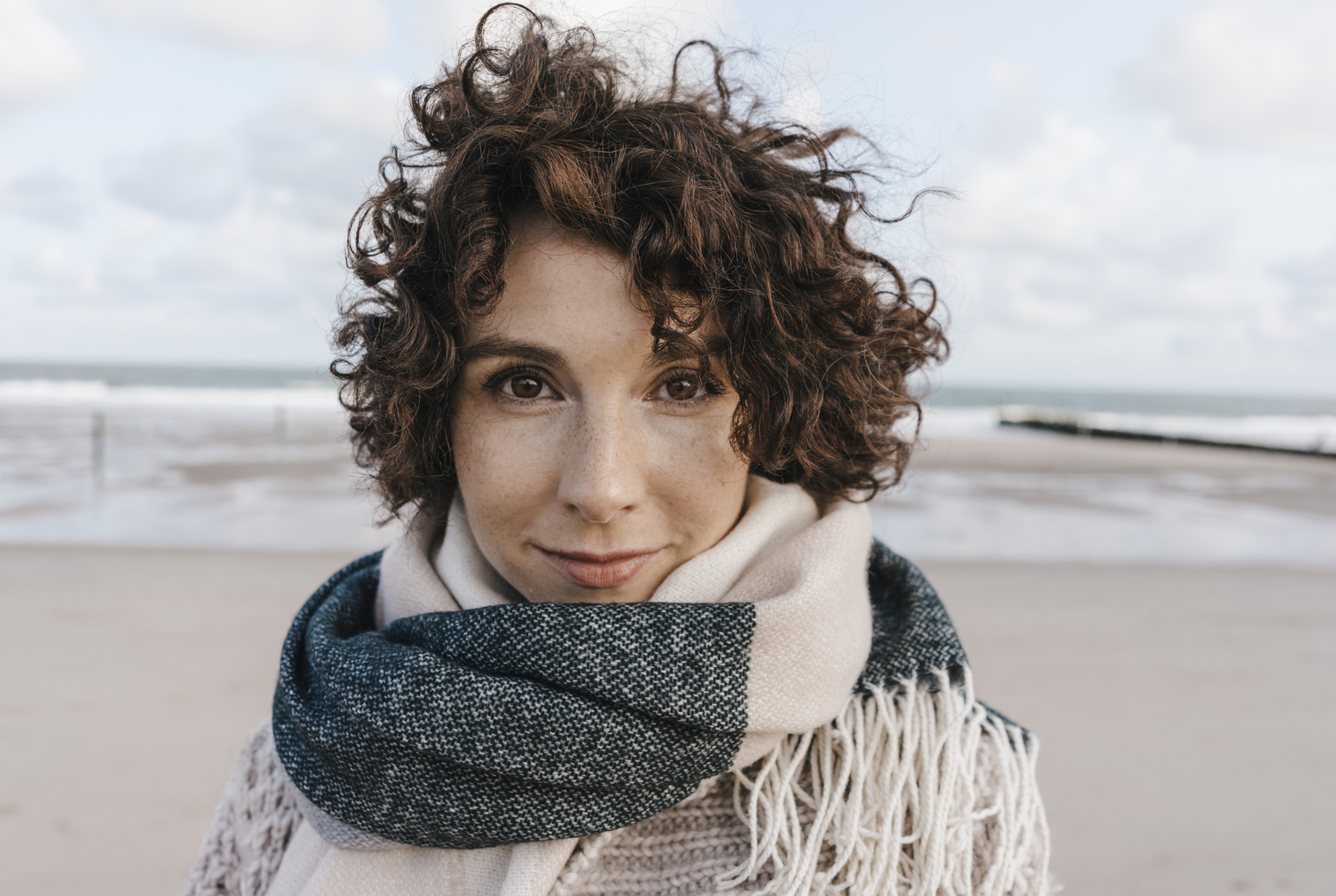 Frau mit warmem Schal am Strand