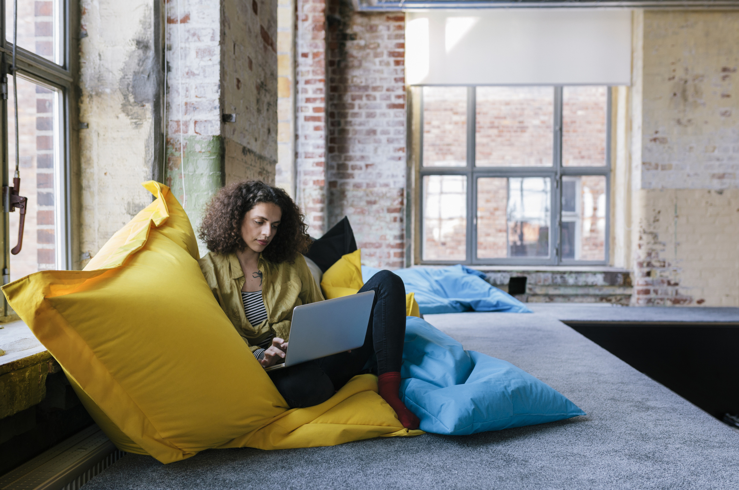 Frau auf Sitzkissen mit Laptop