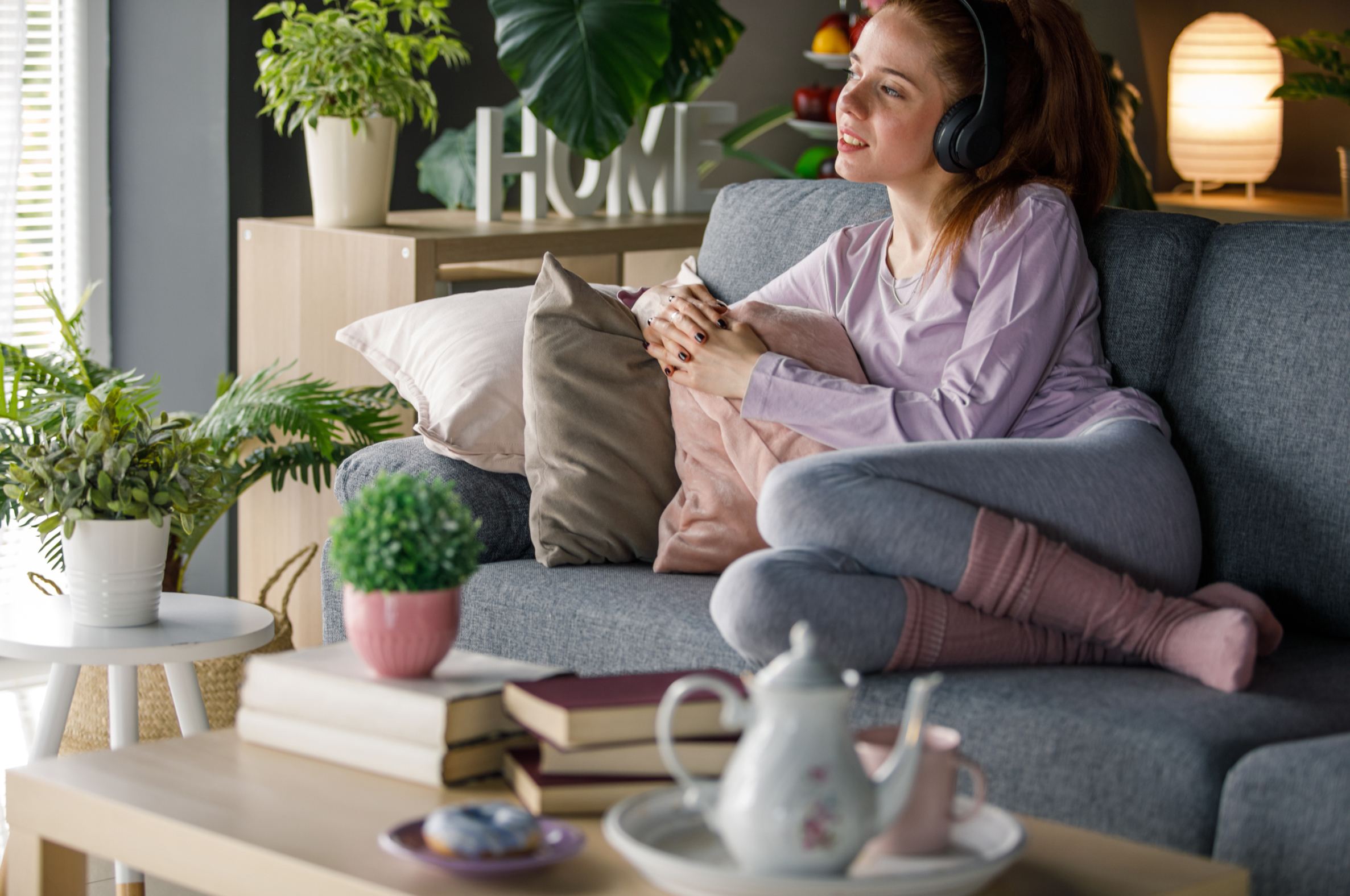 Frau auf der Couch hört Hörbuch