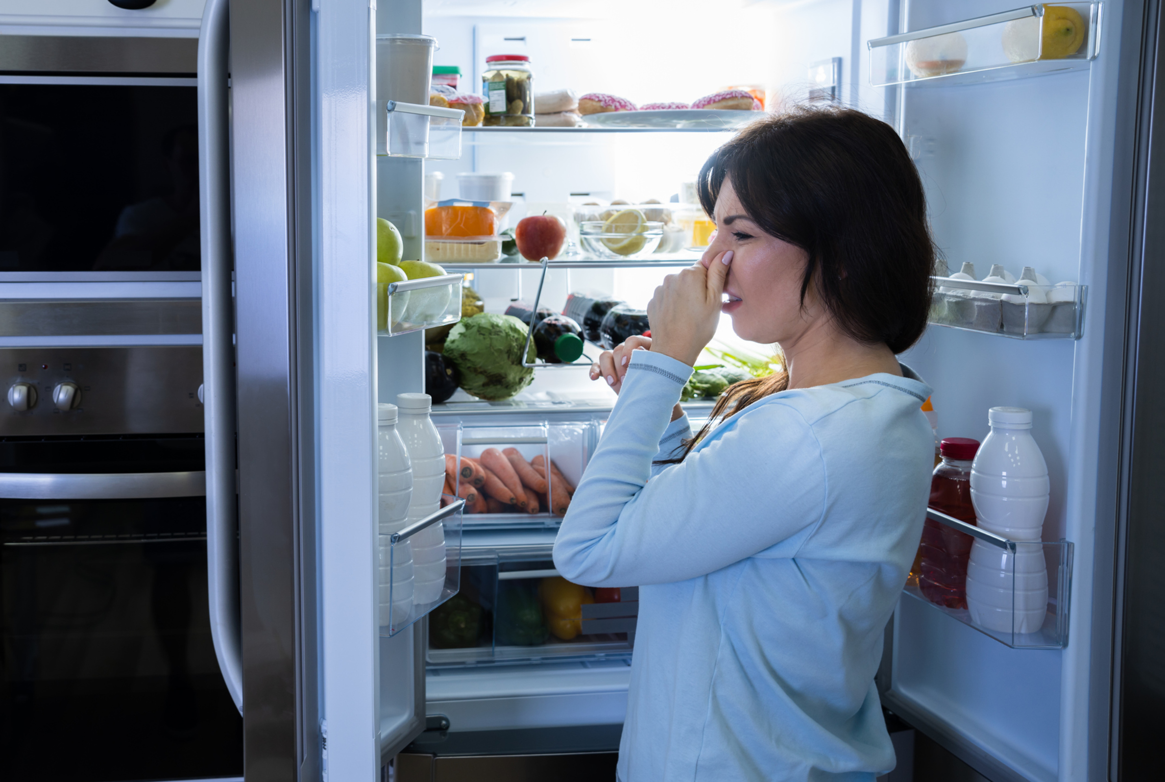 Frau am Kühlschrank hält sich Nase zu