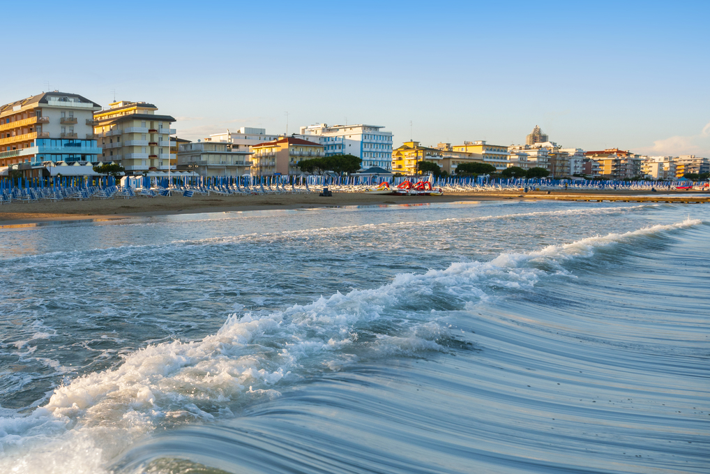 Strand mit zugeklappten Sonnenschirmen und Häuser im Hintergrund