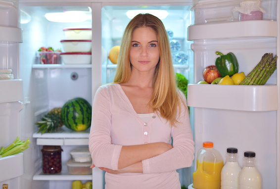Frau steht vor Kühlschrank