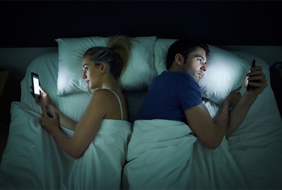 Ehepaar im Bett mit Smartpohne