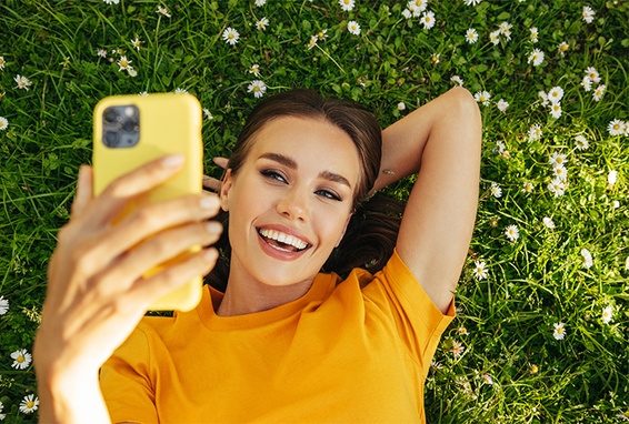 Eine schöne Frau macht ein Selfie auf dem Rasen