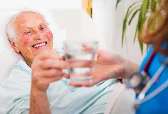 ältere Dame im Bett und Wasserglas