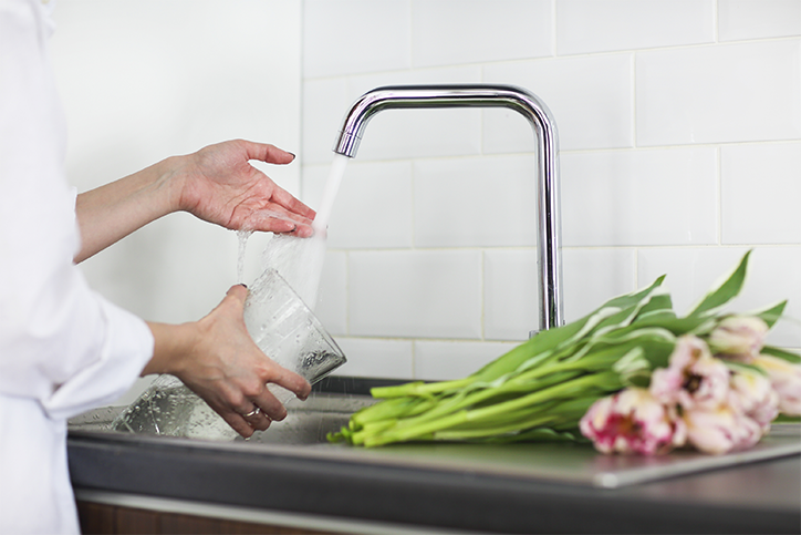 Frau füllt Wasser in eine Vase