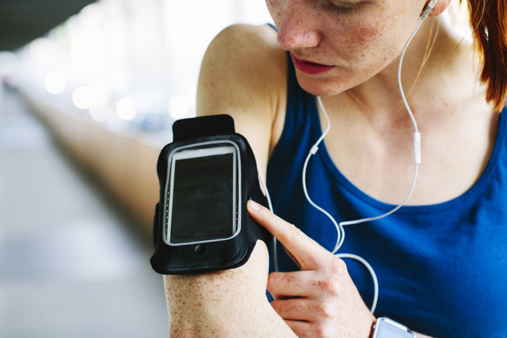 Frau hat Handyhalterung zum Joggen am Arm
